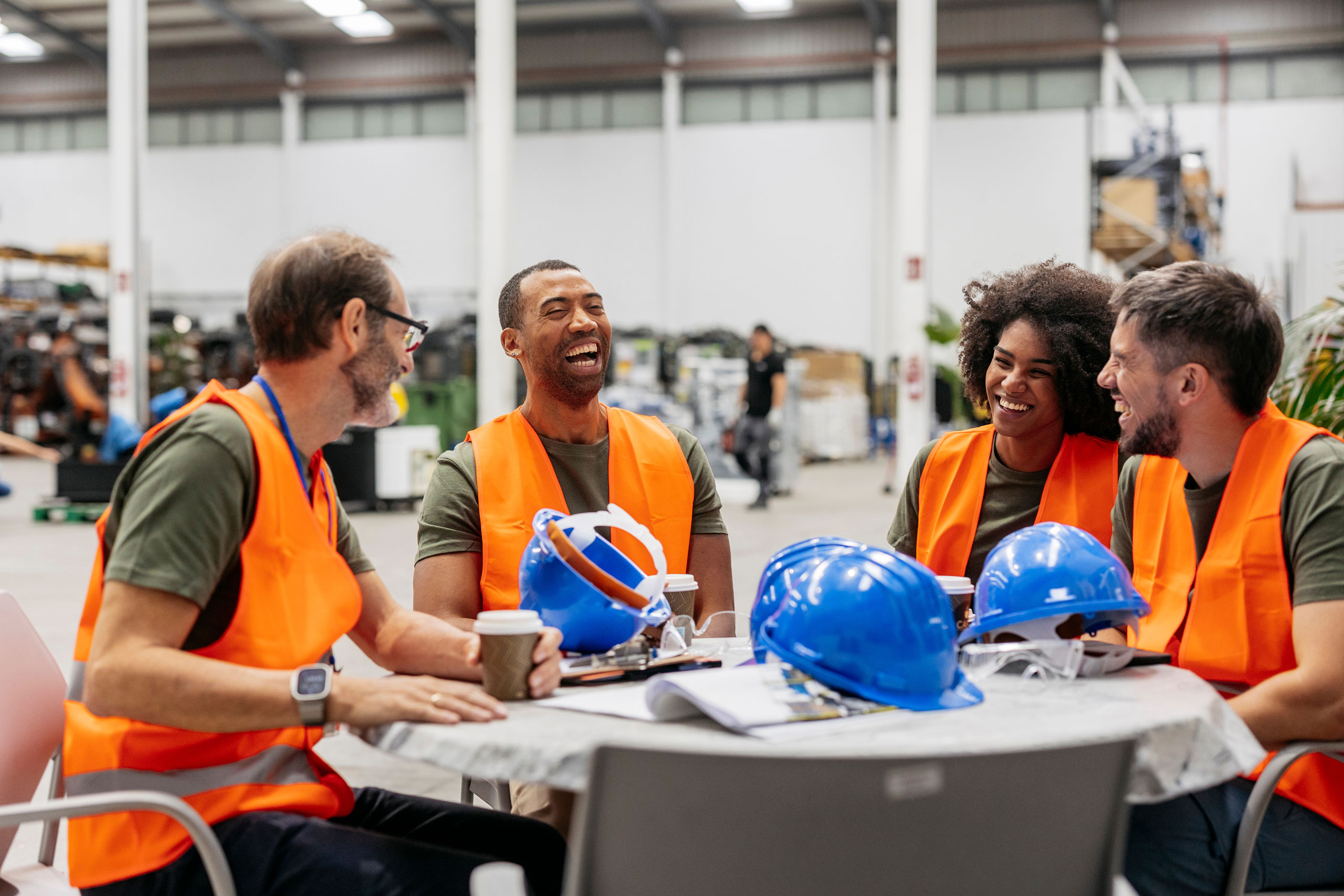 Engineering team enjoying a coffee break in a factory, representing OccuMedX employee wellness