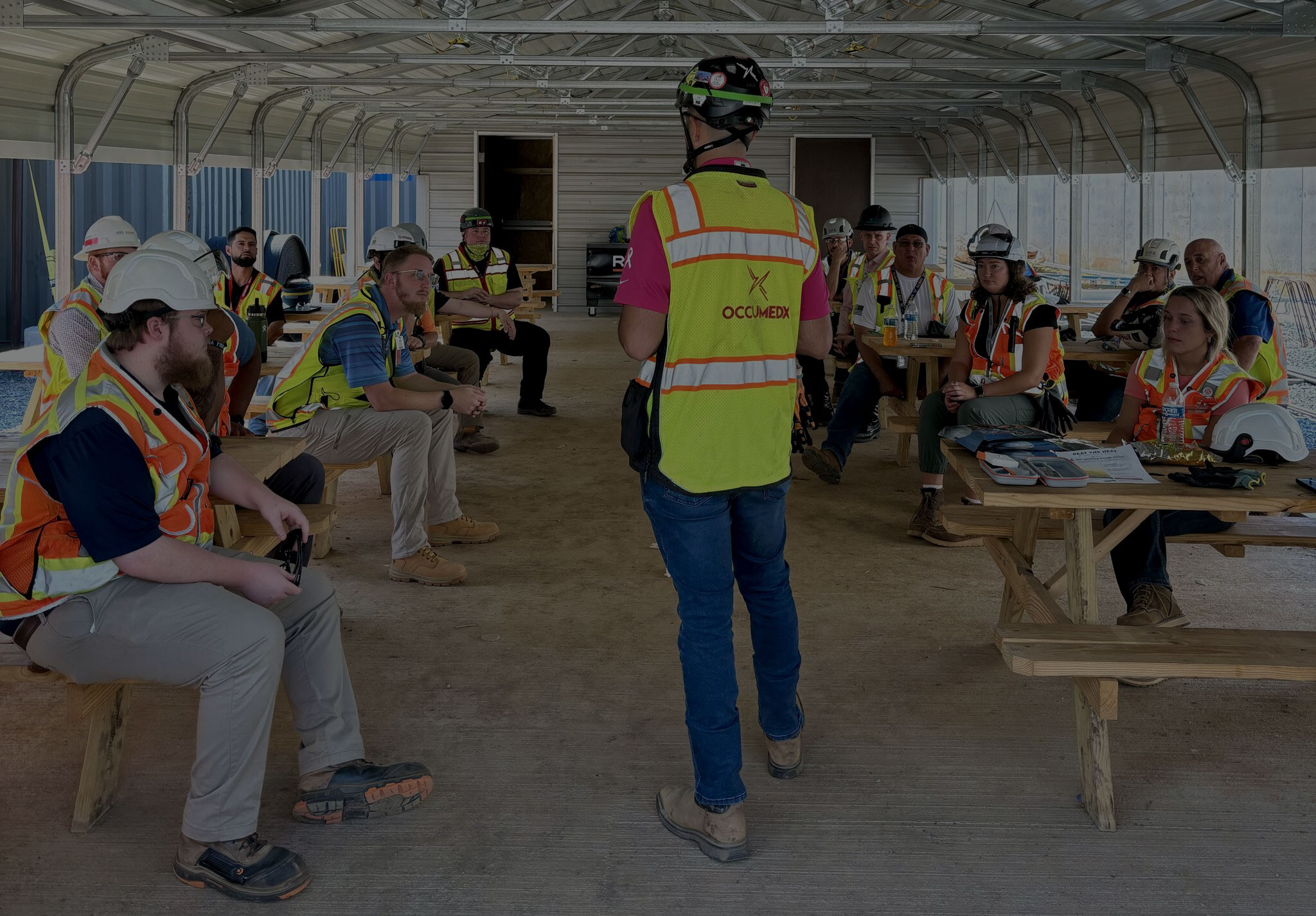 OccuMedX team member leading a discussion with other team members under an onsite tent