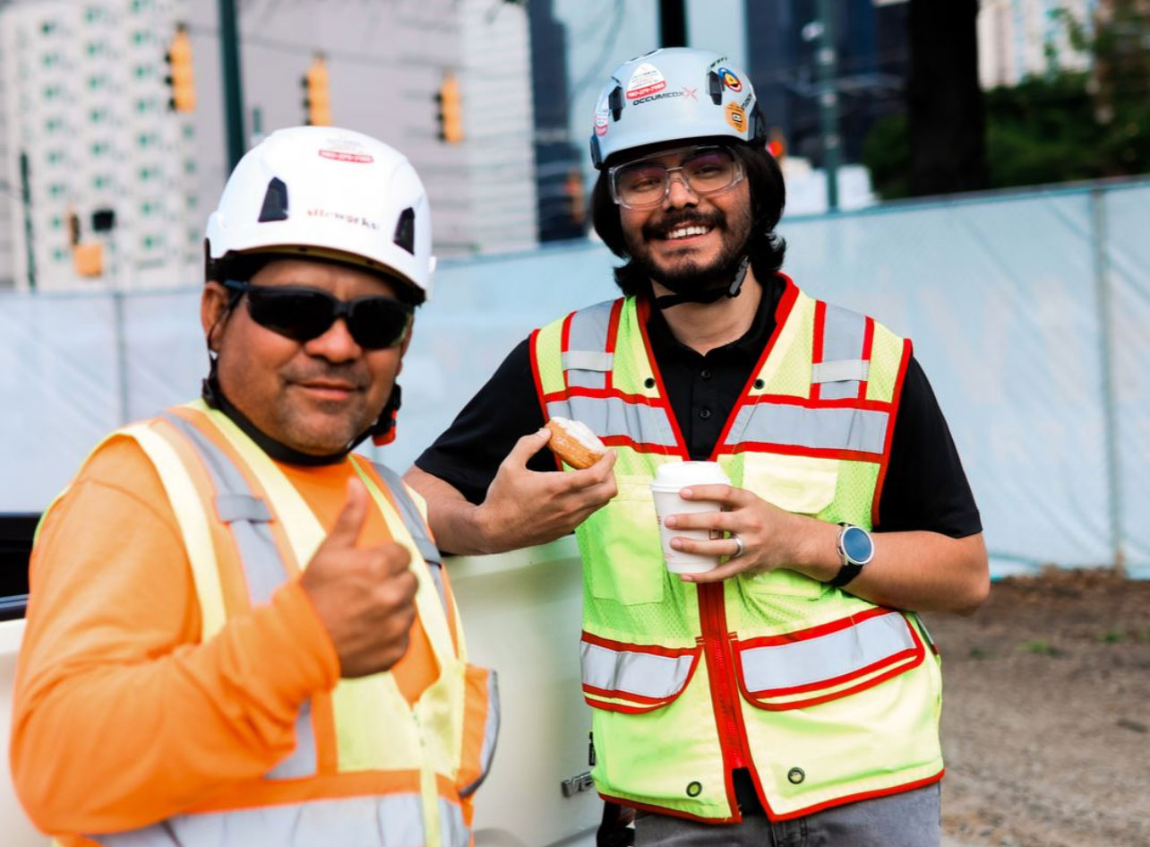 Two OccuMedX team members in hard hats and safety vests smiling at a Charlotte, NC job site